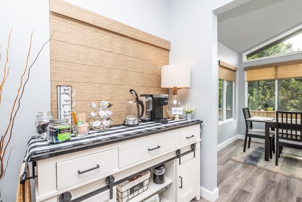 A kitchen with a striped countertop, a coffee maker, and a dining area with a table and chairs.