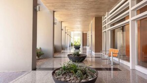 A corridor with a modern design, featuring a bench and potted plants along the walls.