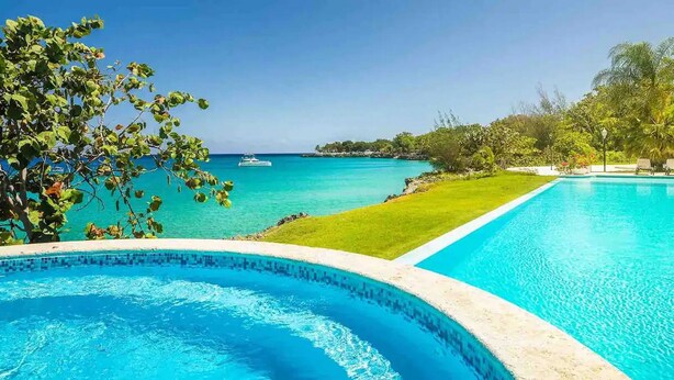 A clear blue pool with a view of the ocean and a well-maintained lawn. - Beachfront residence in central Sosua, 2BD/2BTH with sea views. Chica-friendly! (Sosúa)