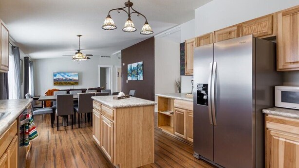 Eine moderne Küche mit Holzschränken, einem Edelstahlkühlschrank und einem Essbereich mit Tisch und Stühlen.