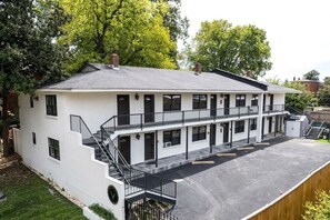 A two-story building with a flat roof, multiple windows, and a covered parking area.
