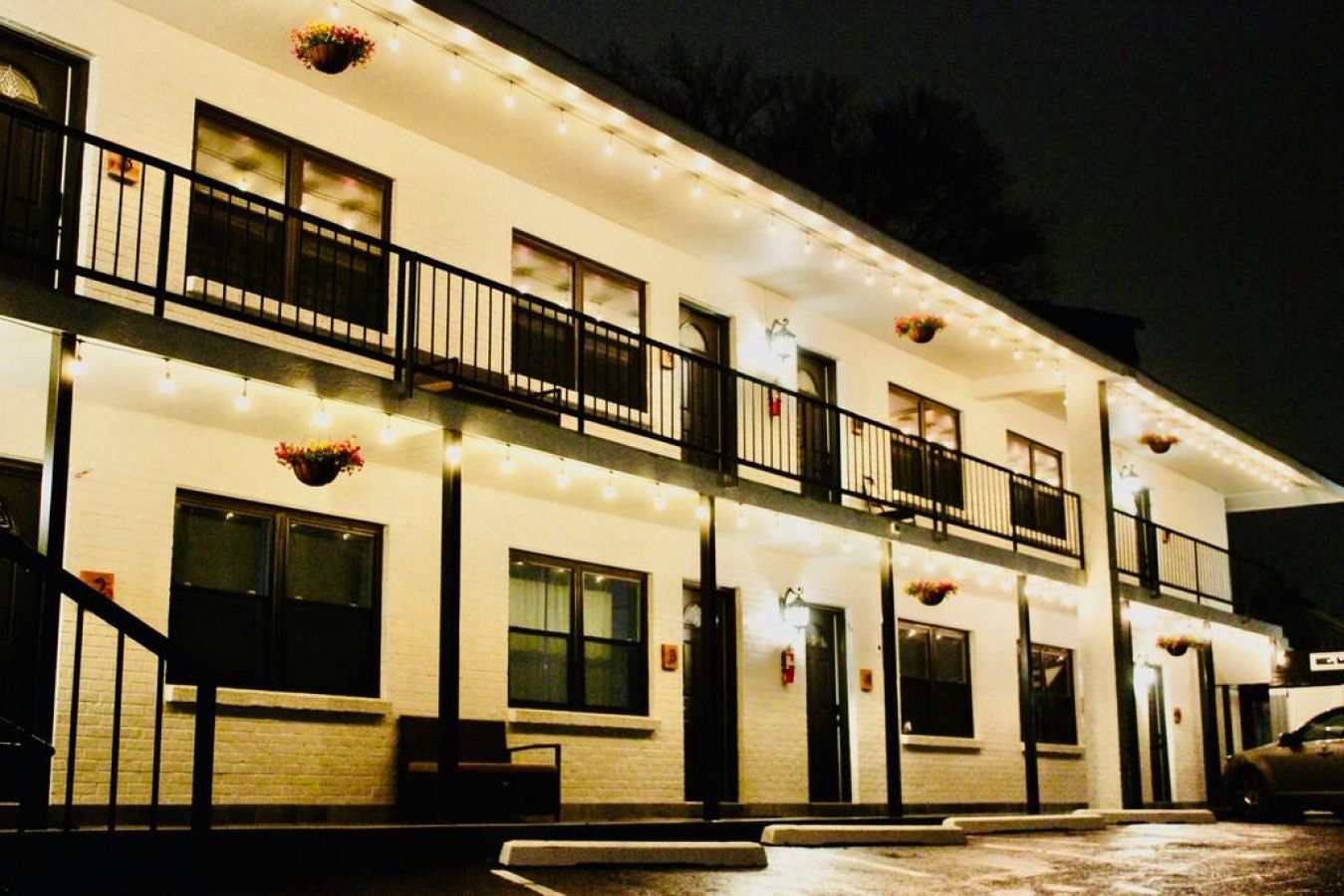 A multi-story building with balconies, string lights, and hanging flower baskets.