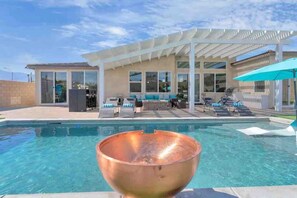A modern pool area with a clear view of the pool, lounge chairs, and a pergola structure.