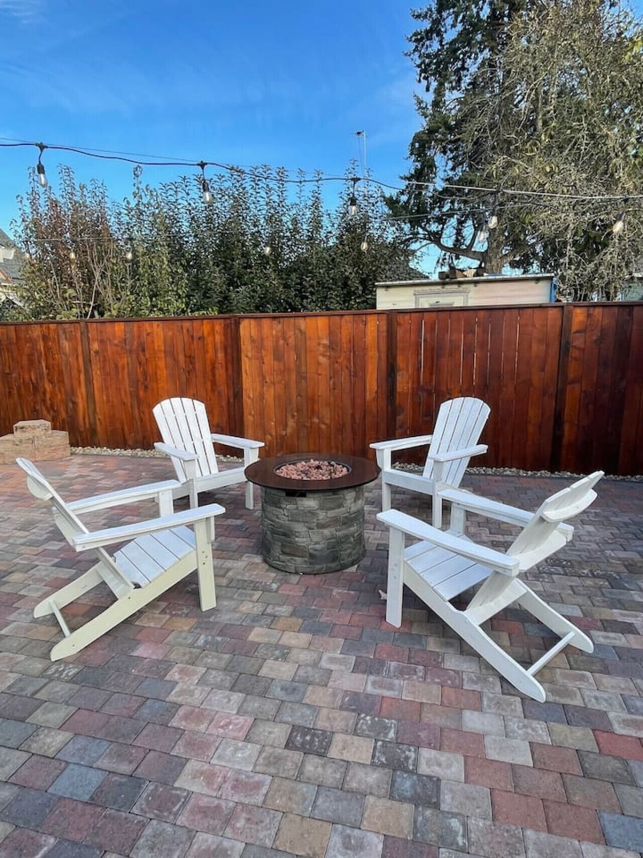 Relax and unwind in this cozy outdoor space, perfect for enjoying the evening under the string lights. Gather around the fire pit with friends or family and soak in the peaceful ambiance of the beautifully designed patio