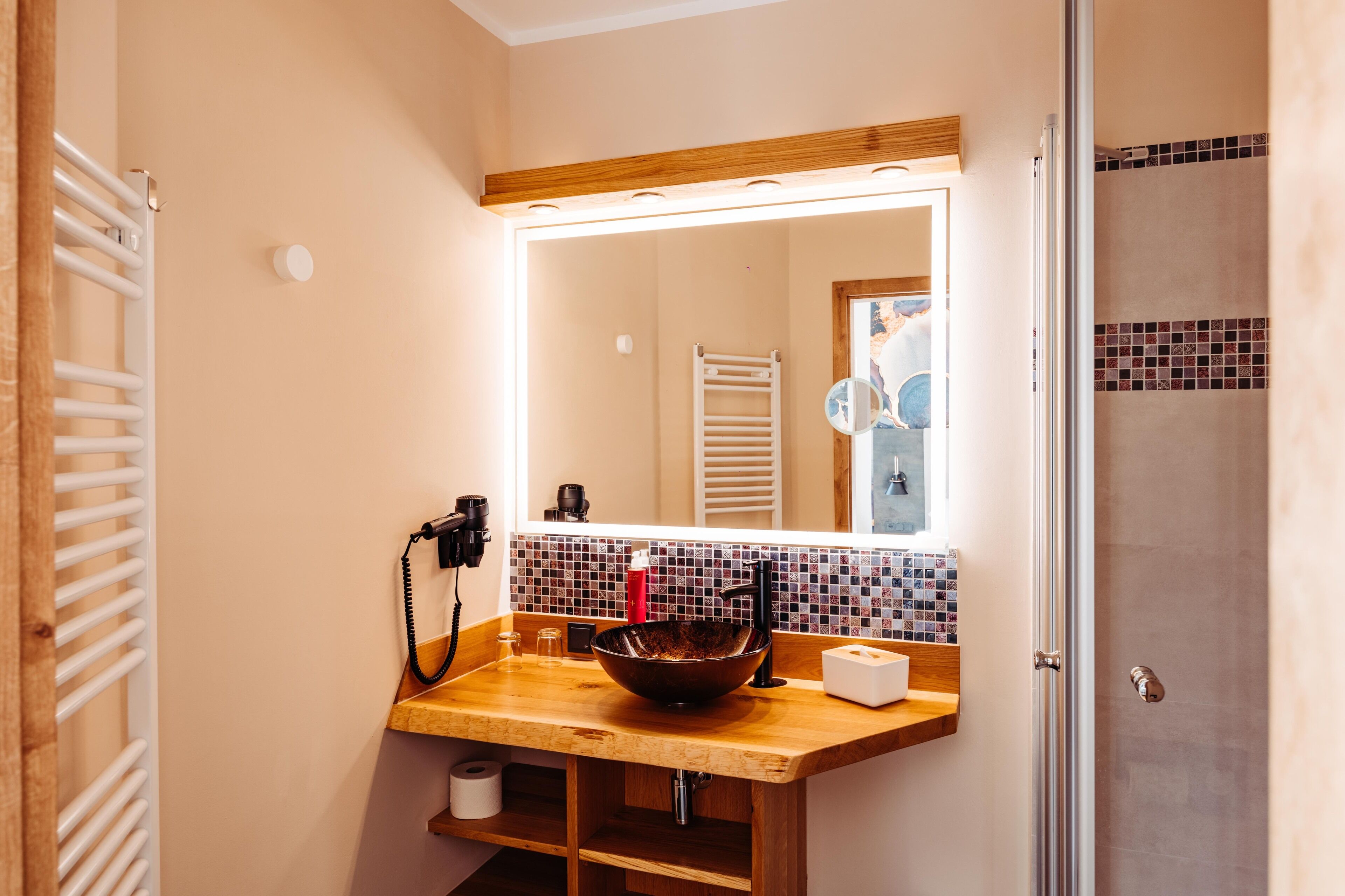 Un baño con tocador de madera, un espejo grande, un perchero para toallas y una zona de ducha.