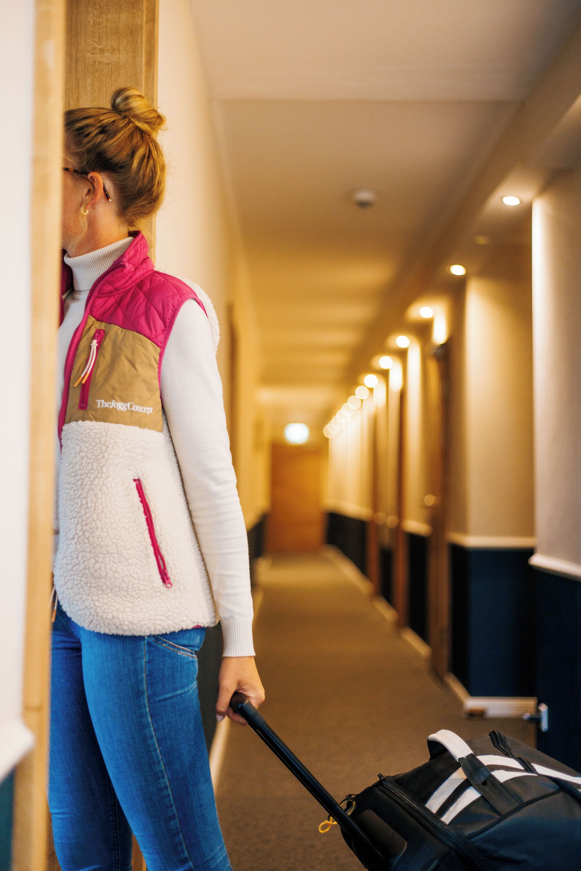 Un pasillo de hotel con una persona cargando una maleta.
