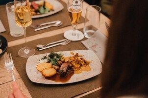 Uma mesa de jantar com pratos de comida, copos de vinho e talheres.