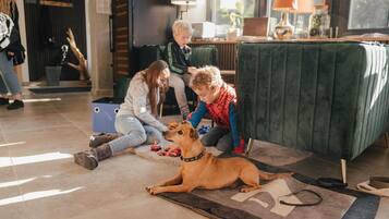 A living room with a green sofa, a dog lying on a rug, and two people interacting with the dog.