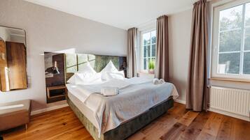 Un dormitorio moderno con una cama grande, una mesita de noche, un espejo y una ventana con cortinas.