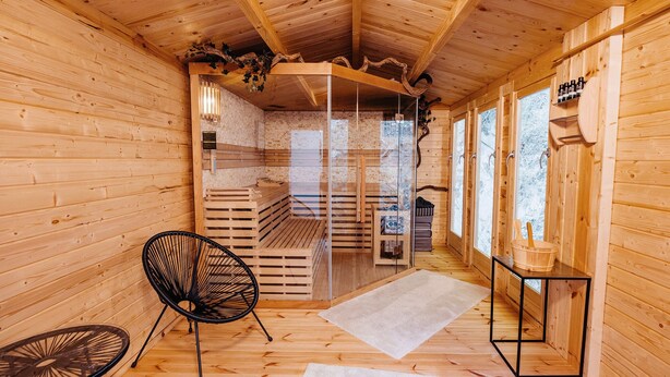 Una sauna de madera con bancos, una silla y una mesa.