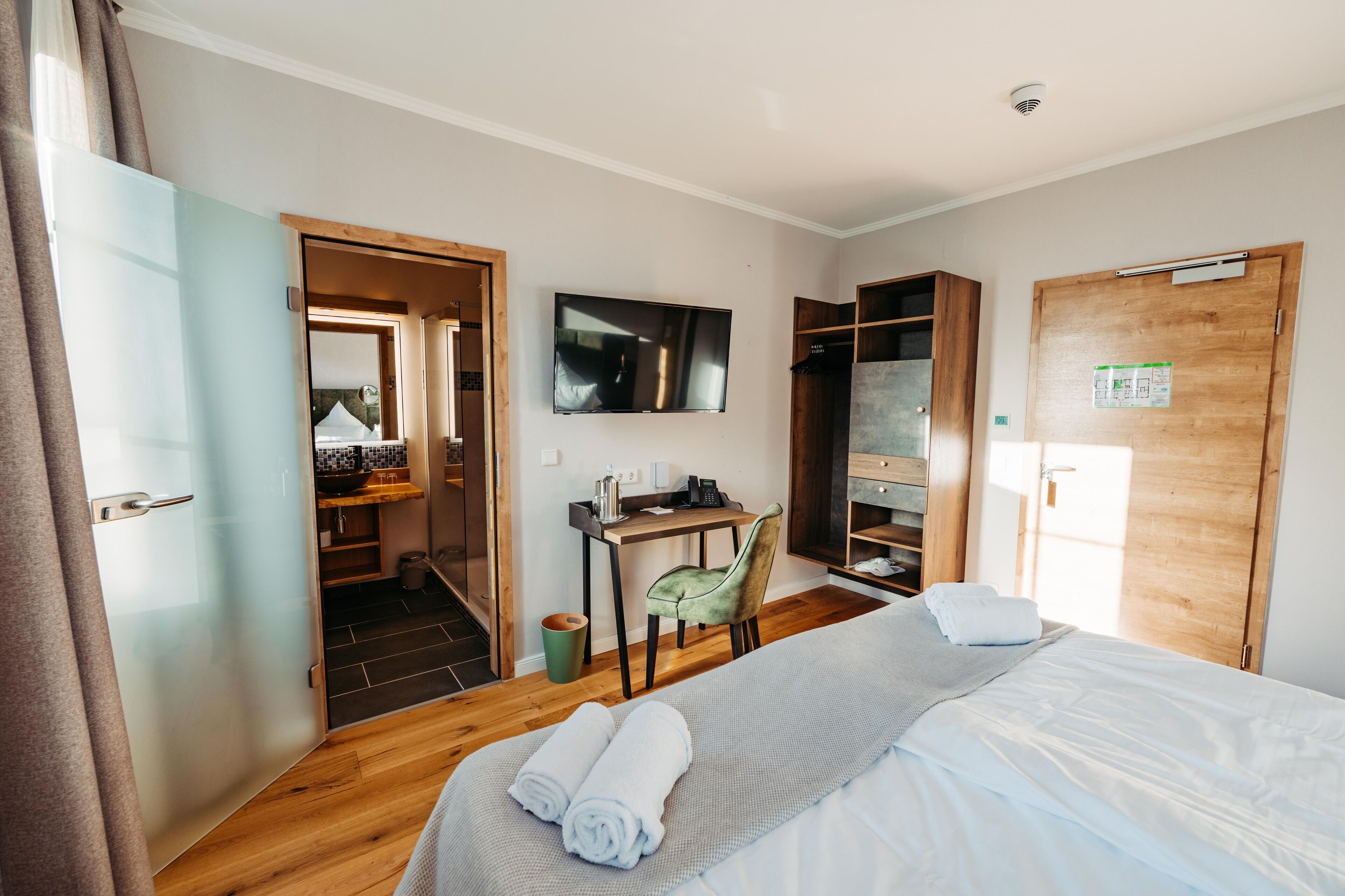 Une chambre d’hôtel comprenant un lit, un bureau, une chaise, une télévision et une armoire.