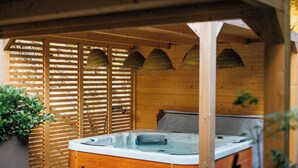 Zona de hidromasaje exterior de madera, con valla de madera y cestas colgantes.