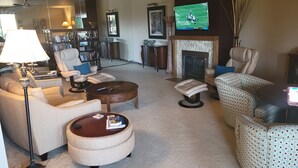 Una sala de estar con chimenea, televisor y estantería.