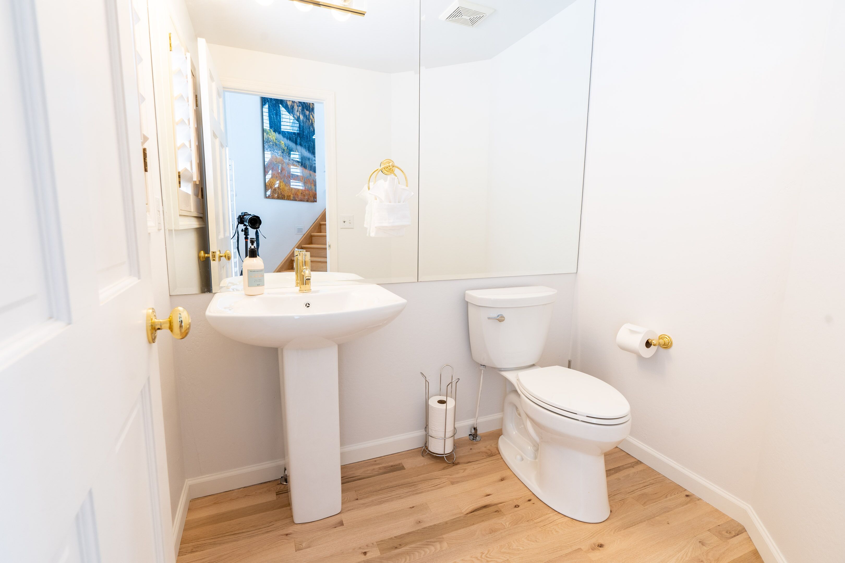 A modern bathroom with a white sink, toilet, and a mirror.