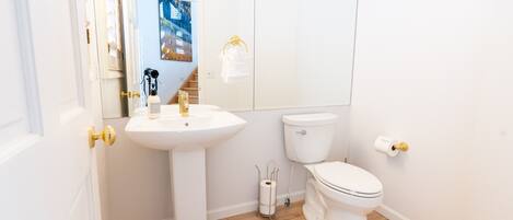 A modern bathroom with a white sink, toilet, and a mirror.