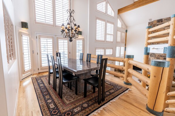 A dining area with a marble table, black chairs, a patterned rug, and a chandelier.