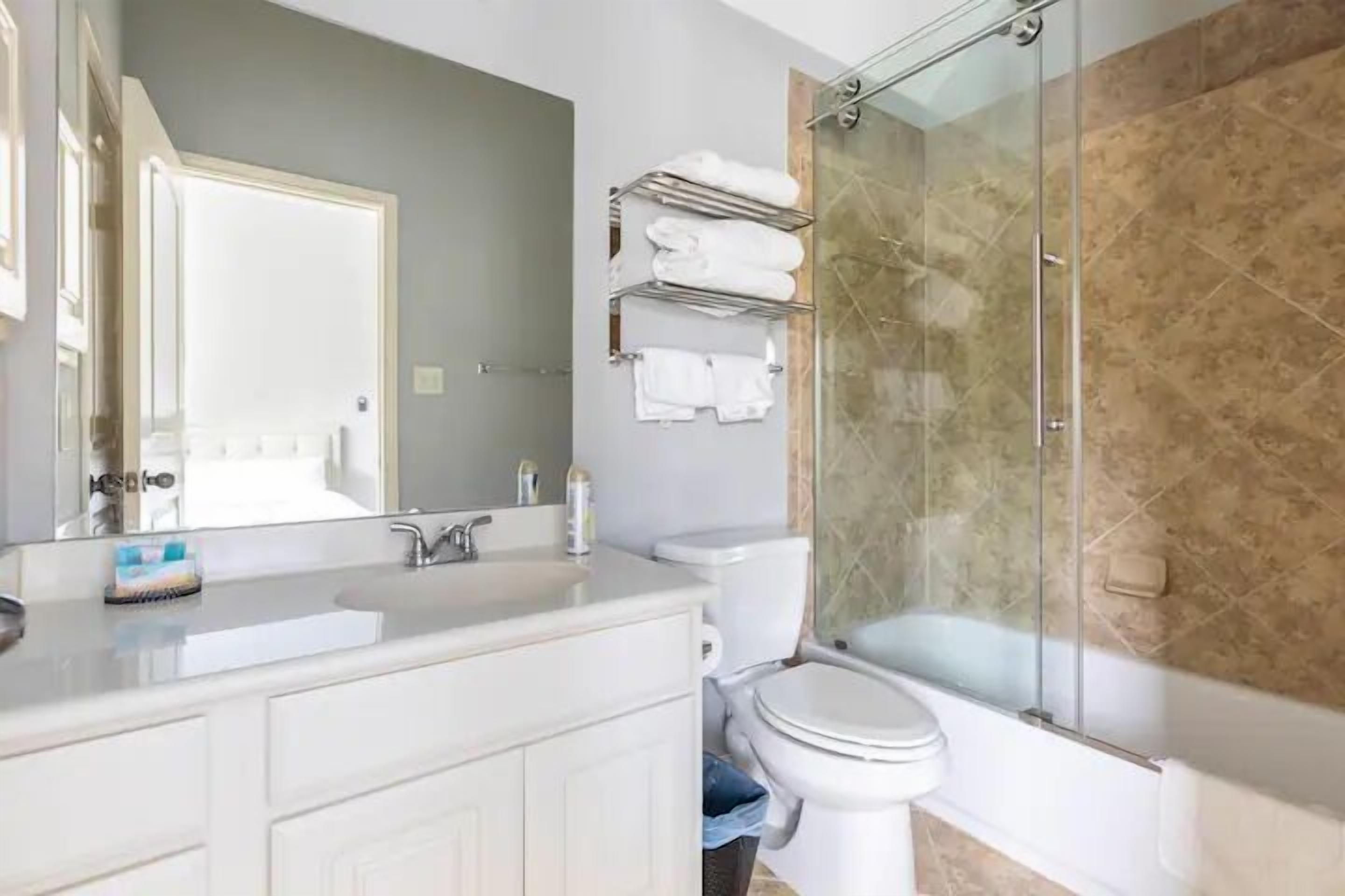 A bathroom with a white vanity, a glass shower enclosure, and a toilet.