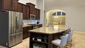 A modern kitchen with dark wood cabinets, stainless steel appliances, and a granite countertop. - Luxury 1 story 3,272 SF. 12 miles from IAH airport (Houston)