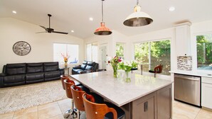 A modern kitchen with a central island, bar stools, and pendant lighting. - Gilbert Ranch Retreat & Non Heated Pool. Walk to Shops and Restaurants. (Gilbert)