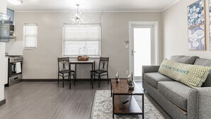 Uma sala de estar moderna com um sofá cinzento, uma mesa de centro e um espaço de jantar com mesa e cadeiras.