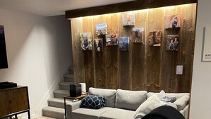 Een moderne woonkamer met een grijze bank, een houten salontafel en een wand versierd met ingelijste foto's.