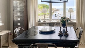 A dining area with a table, chairs, a view of the sea, and a cabinet with drawers. - 3 bedroom awesome home in Vallda (Vallda)