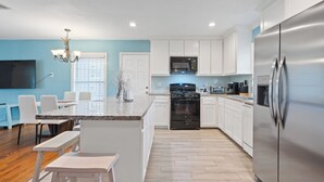 Una cocina moderna con armarios blancos, electrodomésticos de acero inoxidable y una isla central con asientos.