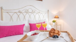 A neatly made bed with white and pink pillows, a tray with breakfast including croissants, berries, and orange juice, and a bedside lamp. - Villa Gamor Frigiliana by Ruralidays (Málaga)