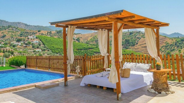 A bedroom with a bed, a wooden pergola, a pool, and a view of a hilly landscape. - Villa Gamor Frigiliana by Ruralidays (Málaga)