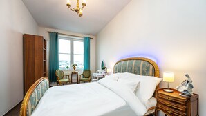 A hotel room with a large bed, a desk with a chair, a dresser, and a window with curtains. - luxury studio 5 (Hlavní mesto Praha)