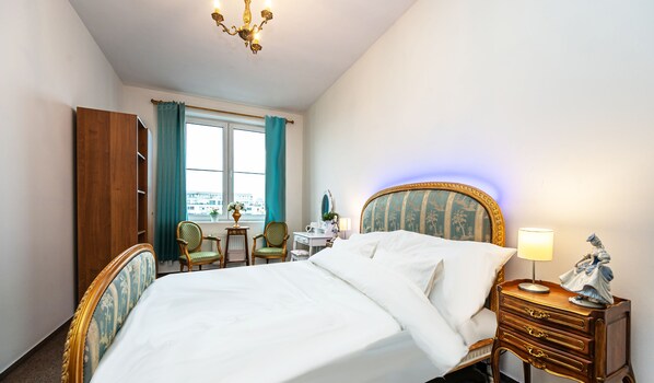 A hotel room with a large bed, a desk with a chair, a dresser, and a window with curtains.