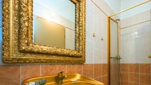 A bathroom with a golden sink, a large ornate mirror, and a shower area. - luxury studio 5 (Hlavní mesto Praha)