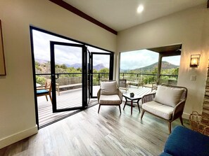 A spacious balcony with a wooden floor, wicker furniture, and a view of mountains. - Stargazer Sedona • 5BR Luxury Retreat • Epic Red Rock Views + Hot Tub (Sedona)