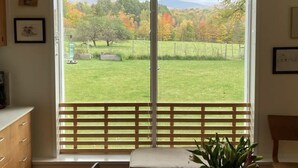 Una habitación con un amplio ventanal corredizo que da a un jardín cubierto de follaje otoñal.