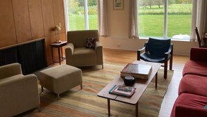 Una sala de estar con sofá, sillones, una mesa de centro y una chimenea.