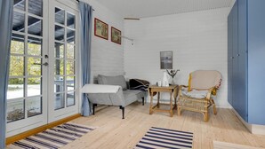 A cozy room with a grey sofa, a wooden table, a wicker chair, and a blue and white striped rug. - Stunning home in Sjællands Odde (Sjællands Odde)