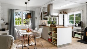 A modern kitchen with white cabinetry, a central island, and a dining area with a table and chairs. - Stunning home in Sjællands Odde (Sjællands Odde)