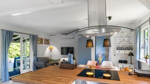 A modern kitchen with a wooden island, stainless steel appliances, and a blue accent wall. - Stunning home in Sjællands Odde (Sjællands Odde)