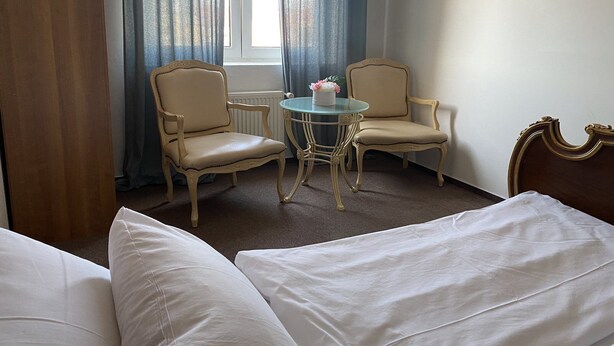 Ein Hotelzimmer mit zwei Einzelbetten, einem runden Tisch mit Stühlen und einem Fenster mit Vorhängen.