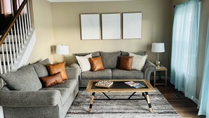 Un salon avec un canapé gris, une table basse en bois et un tapis à motifs.