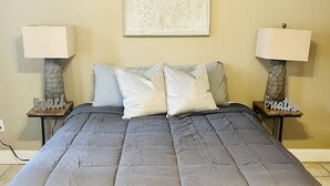 Une chambre à coucher avec un grand lit, deux tables de chevet avec des lampes et un élément décoratif mural au-dessus du lit.