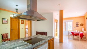 A kitchen with a built-in stove, a large window, and a dining area with a red tablecloth. - 5 bedroom amazing home in Cartagena (Cartagena)