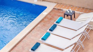 A poolside area with a tiled floor, a pool, and several white lounge chairs with blue towels. - 5 bedroom amazing home in Cartagena (Cartagena)