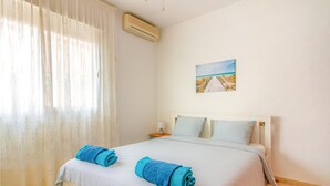 A hotel room with a bed, a painting of a beach, and an air conditioning unit. - 5 bedroom amazing home in Cartagena (Cartagena)