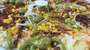 A pizza with toppings like corn, onions, and green peppers.
