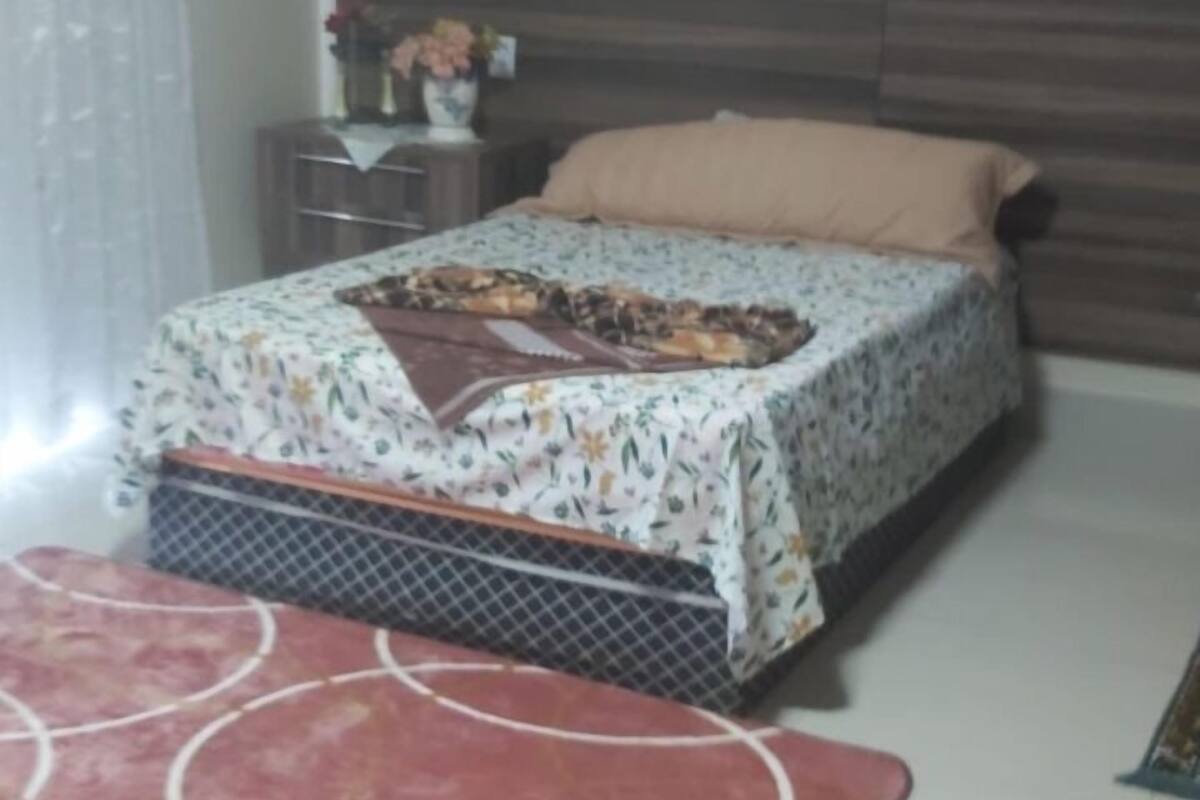A bedroom with a bed, a nightstand, a table, and a chair.