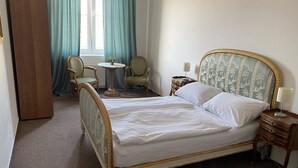 Una camera da letto ordinata con un letto grande, un comodino, una sedia e un tavolino rotondo.