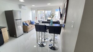 A modern kitchen with a refrigerator, dishwasher, and a dining area with a table and chairs. - TURTUGA AT BIDA MARINO RESIDENCE (Noord)