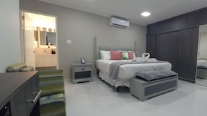 A modern bedroom with a bed, bedside tables, a mirror, and a wardrobe. - TURTUGA AT BIDA MARINO RESIDENCE (Noord)