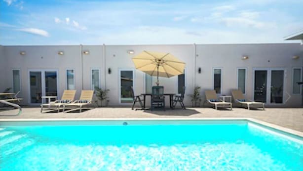 A swimming pool with lounge chairs and an umbrella. - TURTUGA AT BIDA MARINO RESIDENCE (Noord)